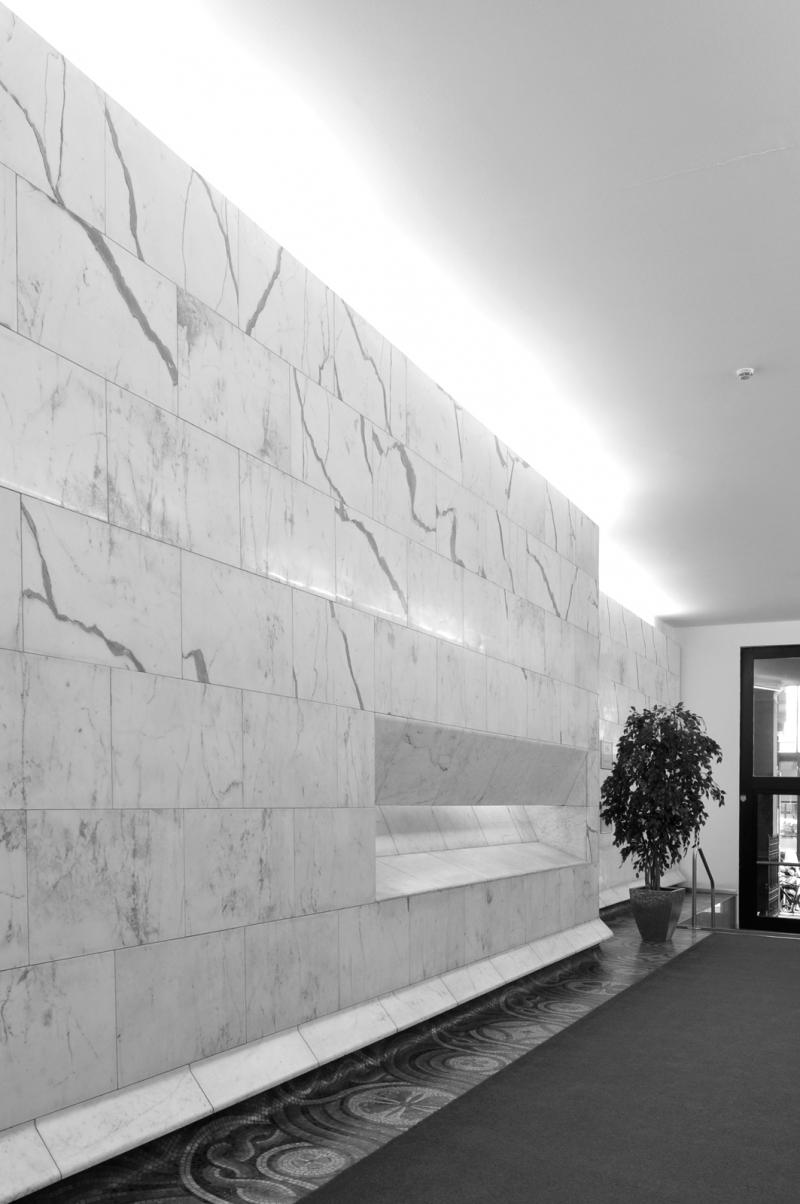 L'atrio della torre, dettaglio del rivestimento in marmo delle pareti, del mosaico a pavimento e della fascia luminosa tra parete e soffitto