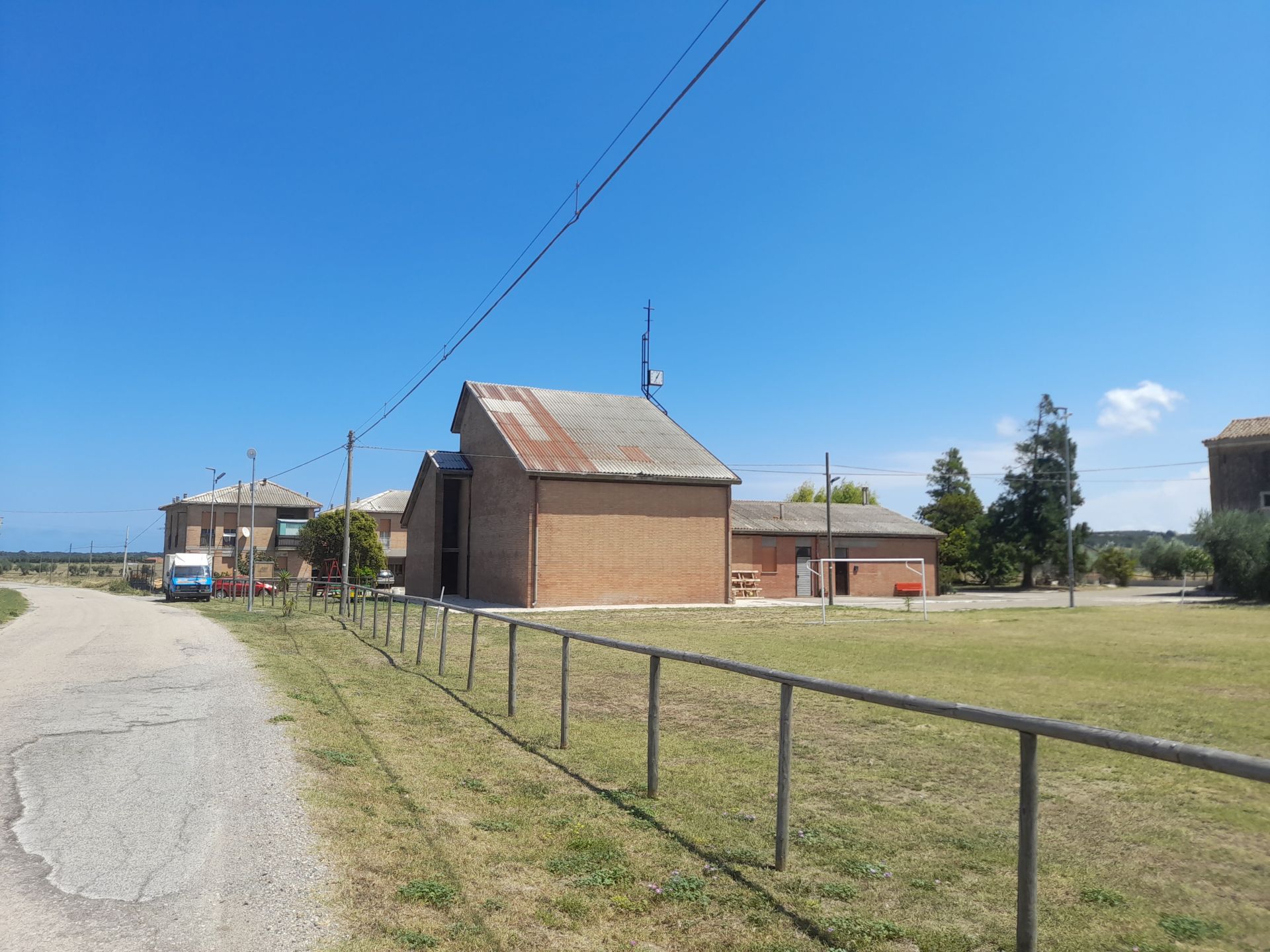 Chiesa e corpo di testa dell'edificio in linea visti dalla strada interpoderale