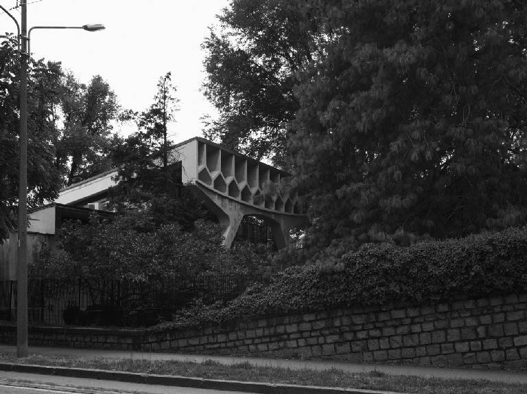 La scuola vista da viale Stelvio, con la trave reticolare che emerge dal verde circostante
