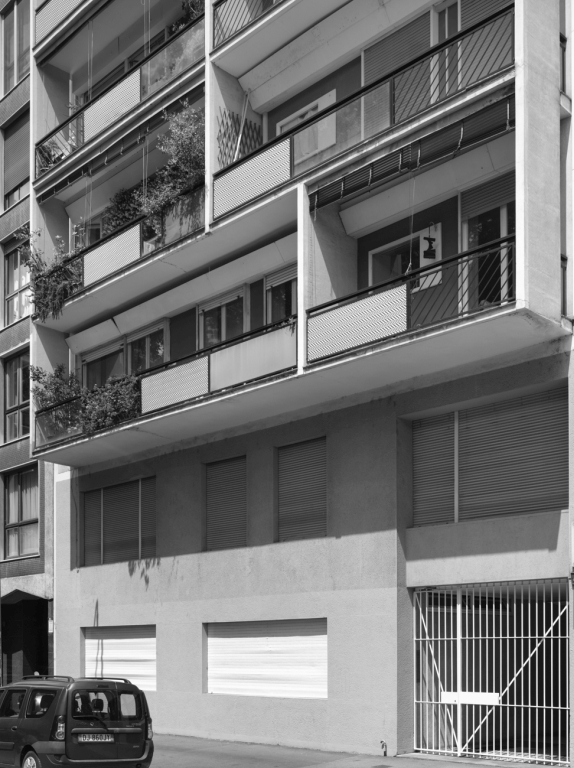 Dettaglio della facciata su via Dezza, con il basamento in pietra da cui si stacca il sovrastante volume svuotato da logge in aggetto